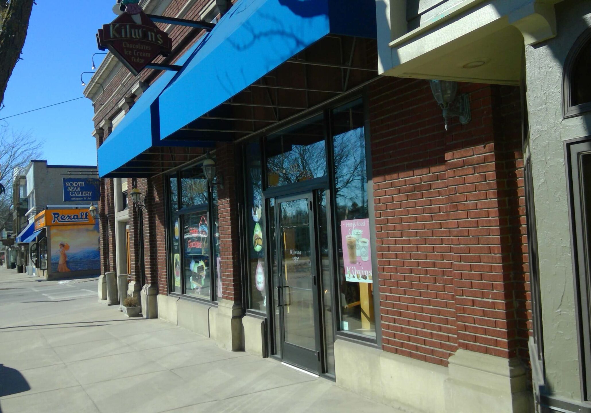 Brick storefronts with blue awnings on sunny street